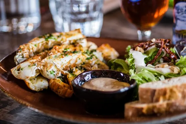 Classic turkey club sandwich stacked high on toasted sourdough with a wooden skewer through the center, served with a side of fresh greens